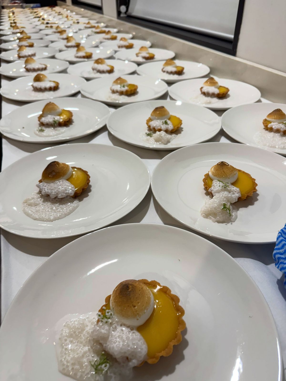 Lemon meringue tart desserts plated in rows for a corporate event