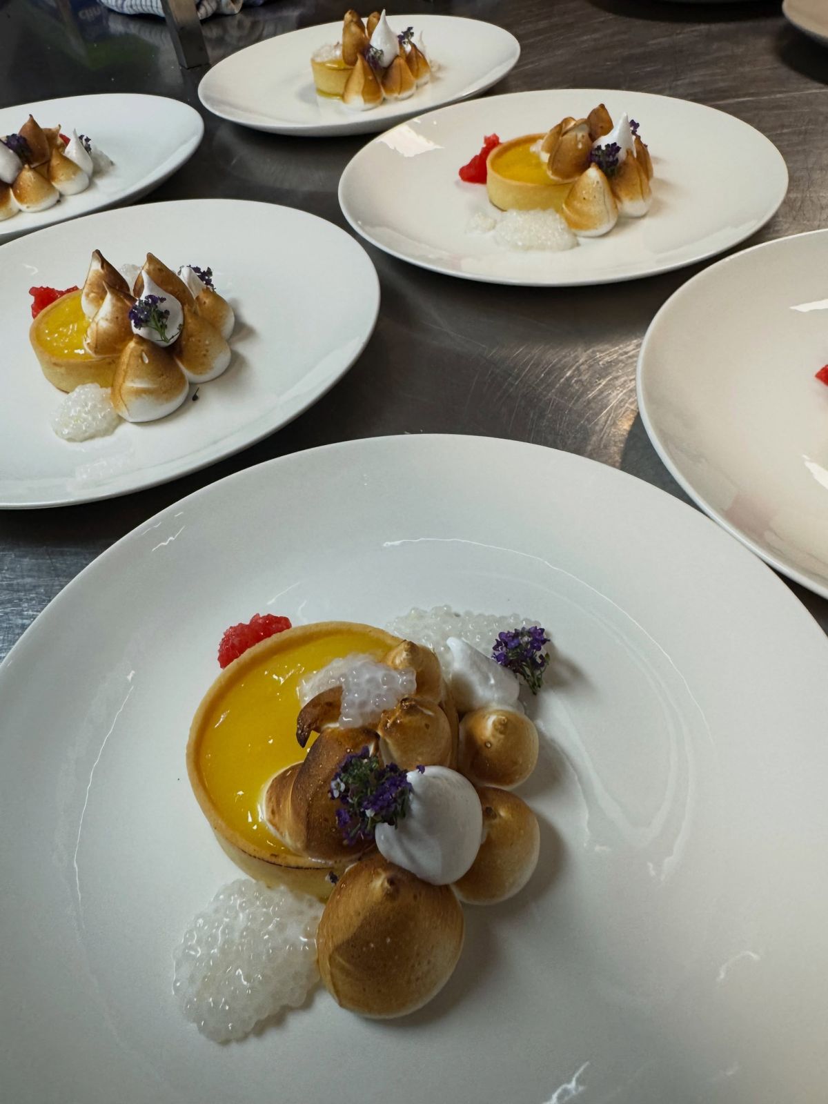Lemon meringue tart dessert with berries and edible flowers