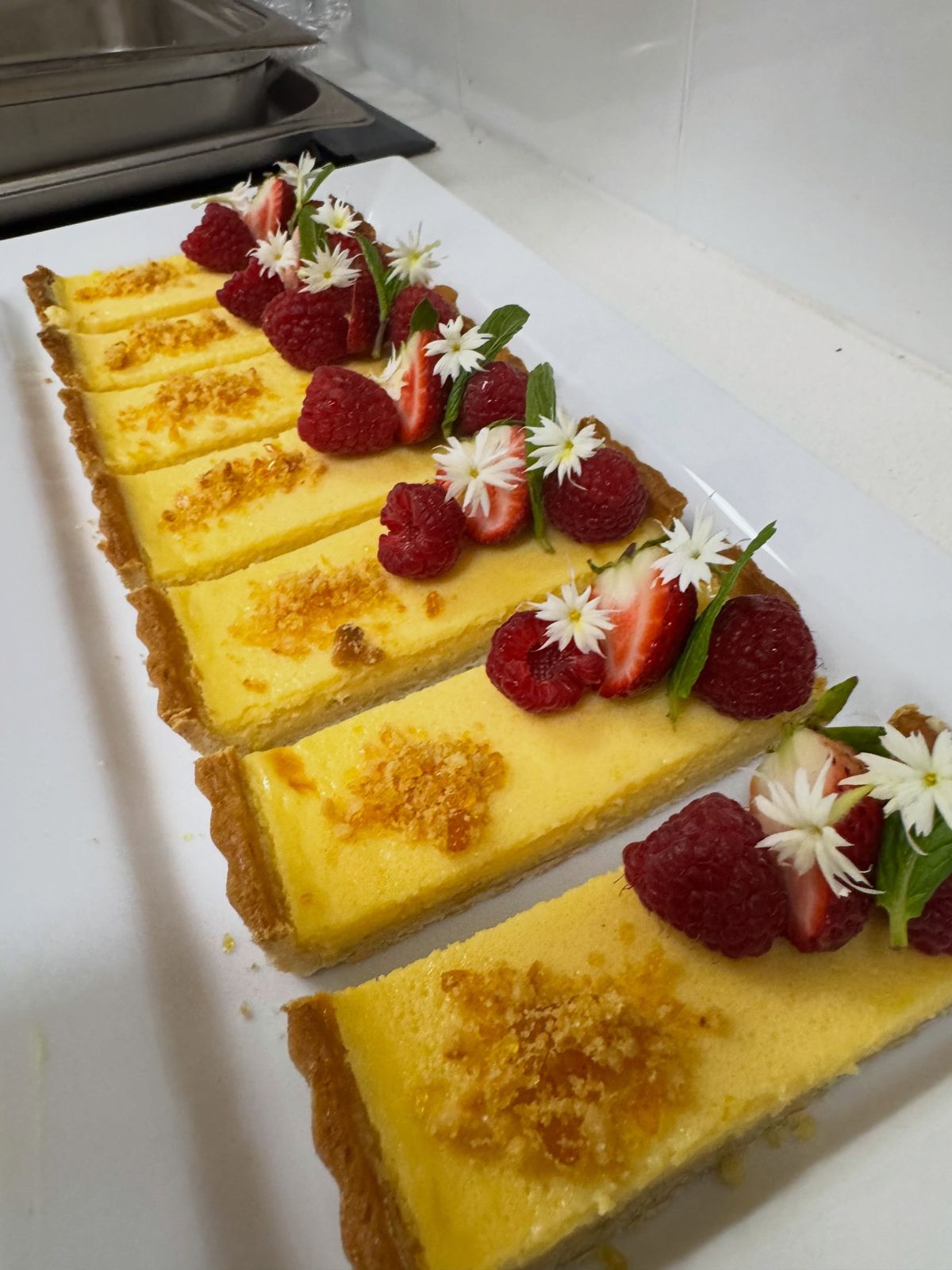 Lemon tart slices topped with strawberries and edible flowers